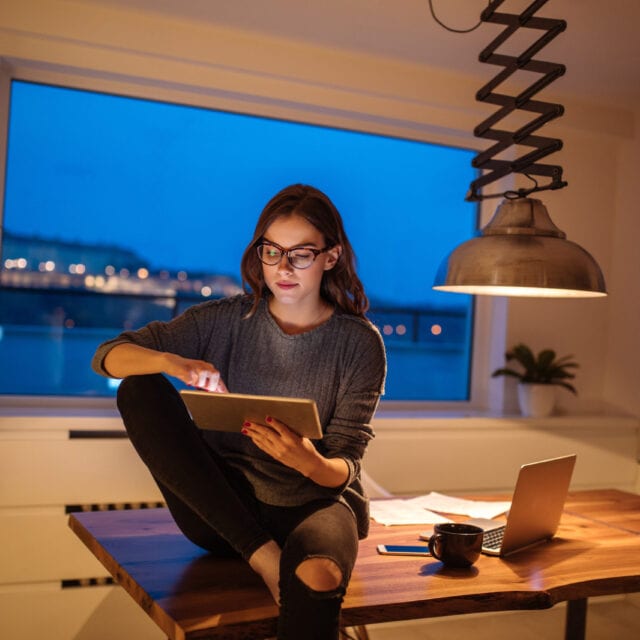 smiling woman uses a tablet. Consumers are advised to watch out for e-transfer and other scams.