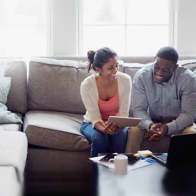 Canadians want government digital identity services: Couple sit on couch with paperwork and laptop